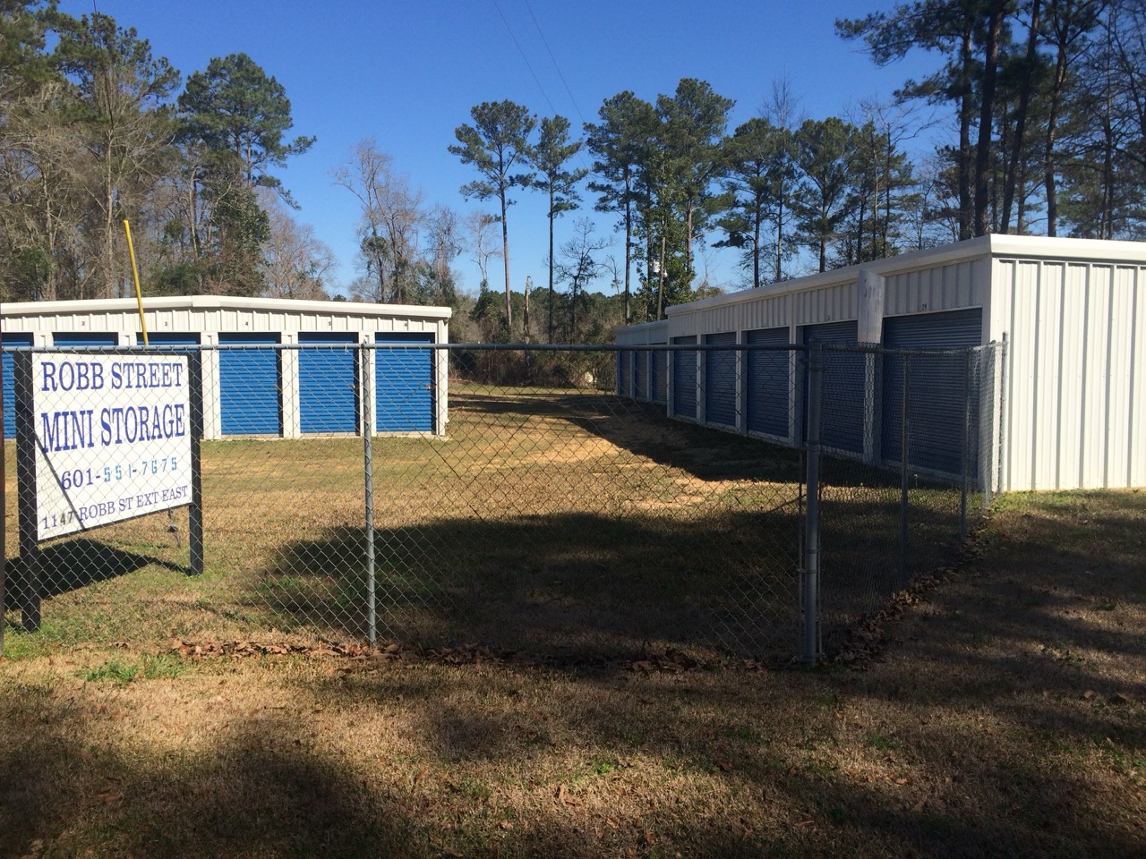 Robb Street Mini Storage sign in front of fenced storage units